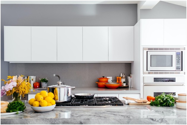 A nice kitchen with pots and pans on the stove and bowls of fruit on the counter