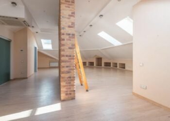 Wooden attic ladder placed in a room with sun coming through the windows